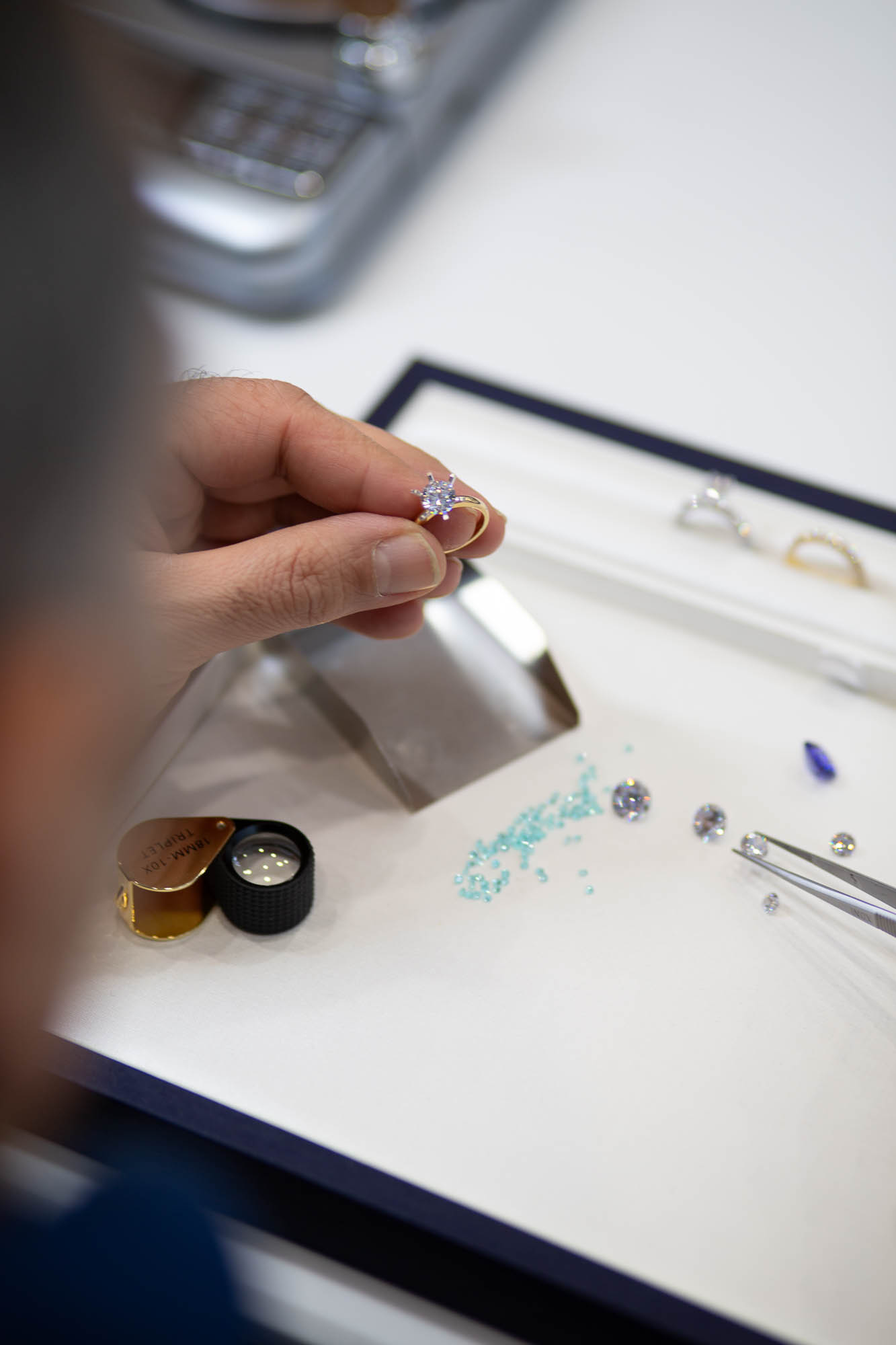 A finished handmade gold ring held over a tray of loose diamonds at the Nathan Jewellers bench